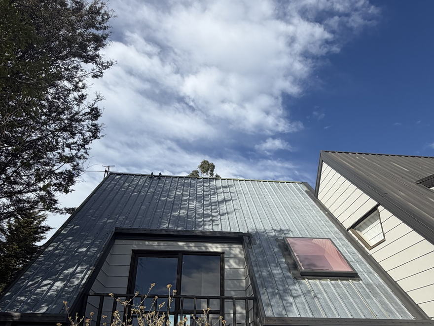 Weathered grey metal roof with chalking and staining before it was cleaned and repainted